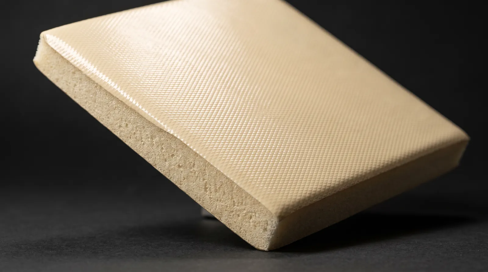 Illustrative cream integral skin polyurethane panel, angled under raking light to show a tool-imprinted surface pattern